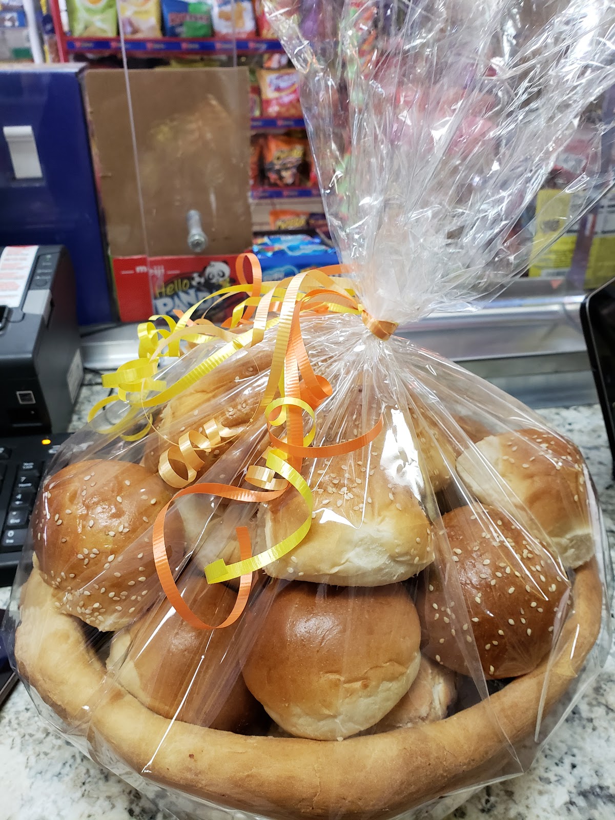 Sesame dinner rolls wrapped as a cellophane gift basket with orange and yellow ribbon