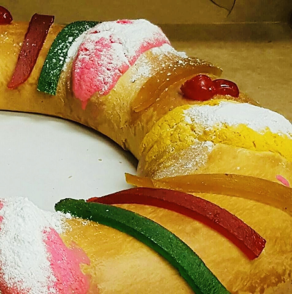 A decorated Rosca de Reyes with candied fruit and sugar paste stripes